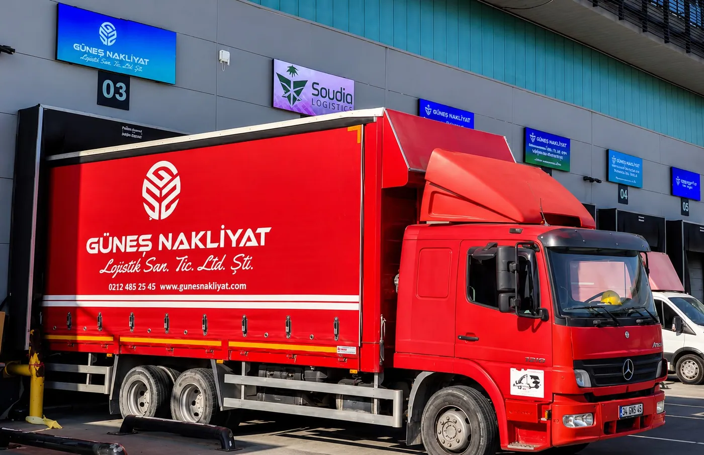 Güneş Nakliyat giydirmeli kırmızı kamyonun kargo terminali rampasında yükleme yapması